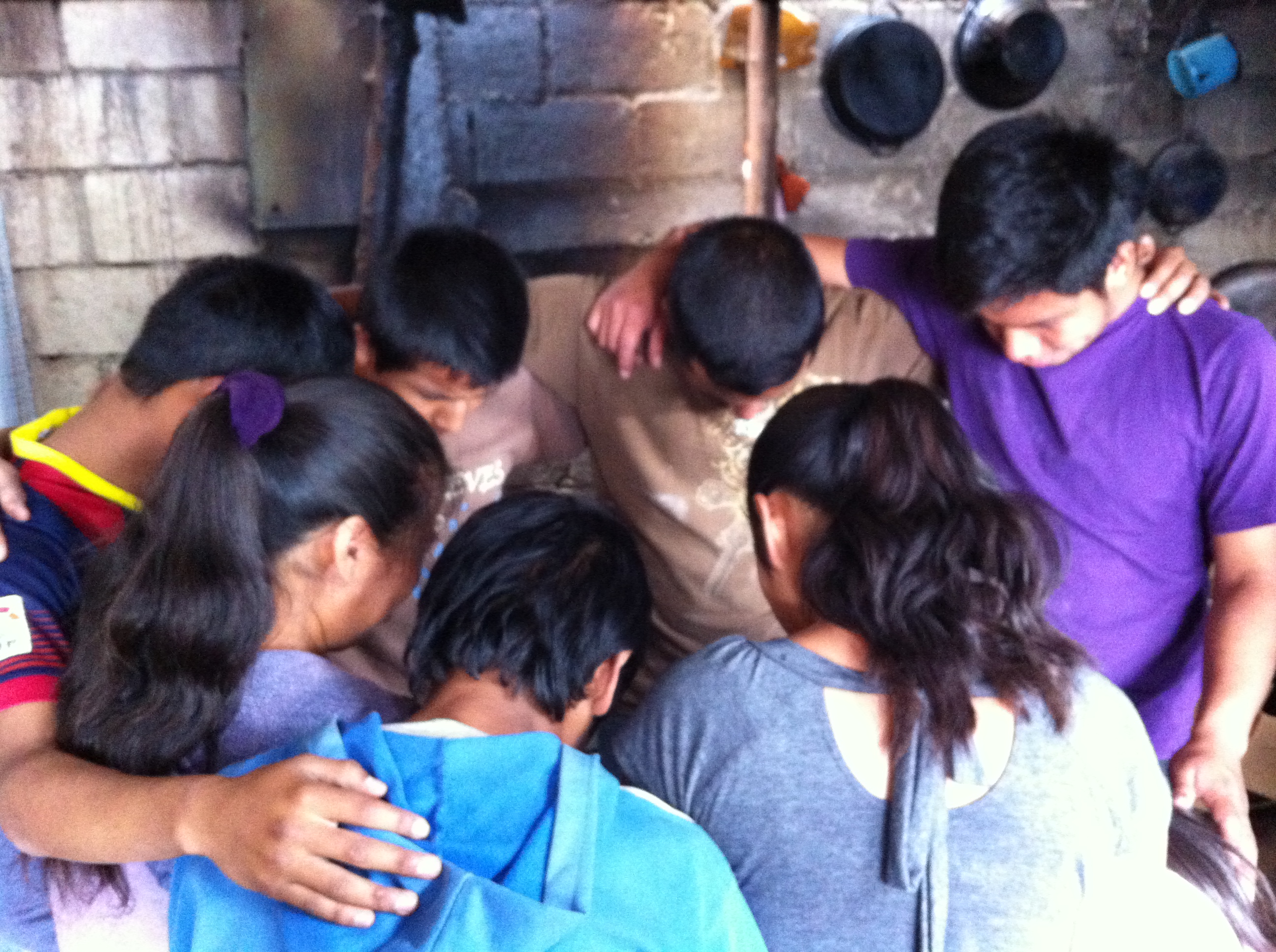 Boys prayin after the 1st installation of a stove for the poor family